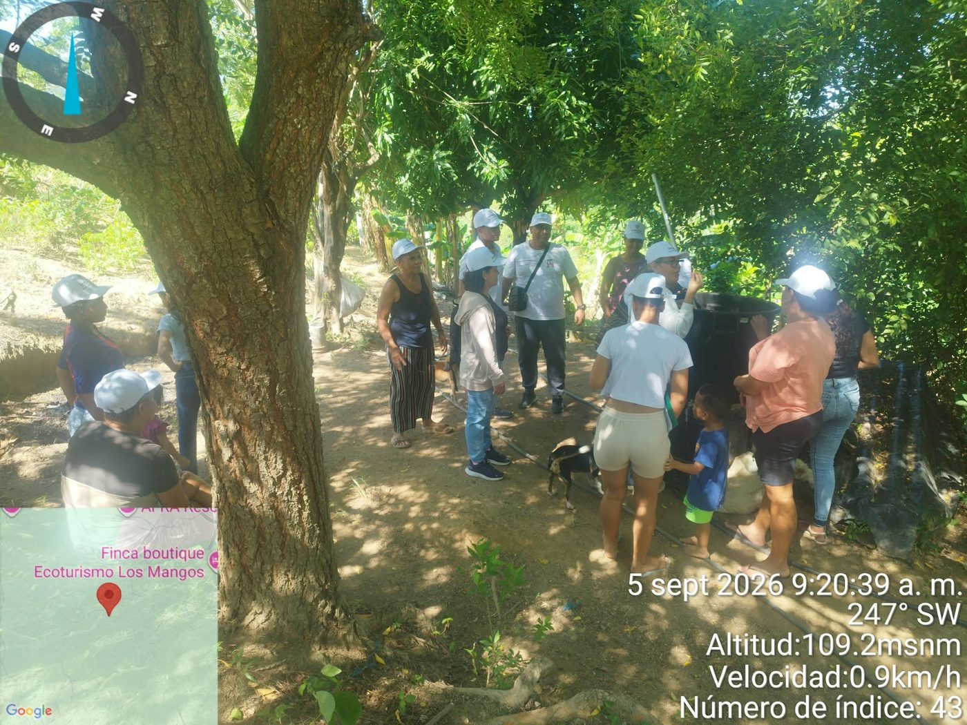 Participantes revisando un tanque de almacenamiento bajo árboles frutales